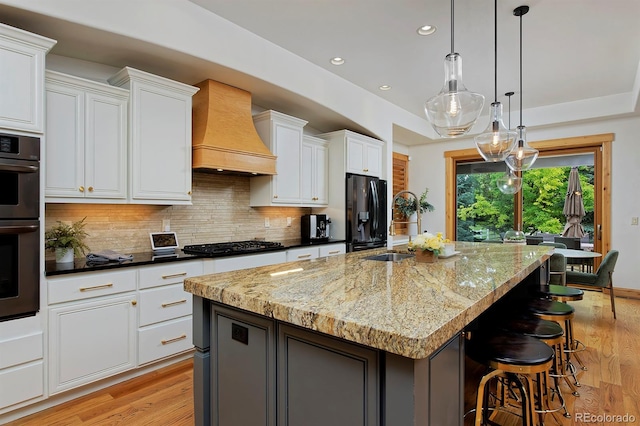14370 Osage St, Westminster, CO 80023 - kitchen featuring premium range hood, light wood-type flooring, black fridge with ice dispenser, a sink, and recessed lighting