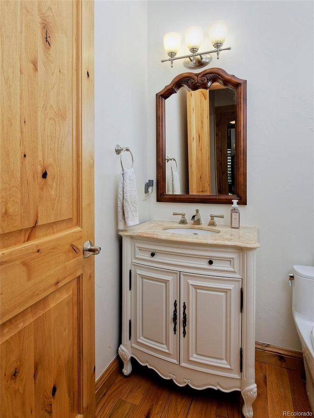 14370 Osage St, Westminster, CO 80023 - half bath with vanity, toilet, wood finished floors, and baseboards