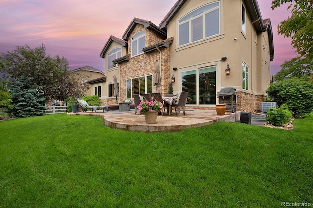 14370 Osage St, Westminster, CO 80023 - rear view of house with stone siding, a patio area, a yard, stucco siding, and central AC