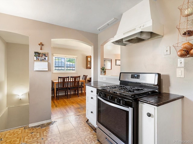 14050 E 25th Pl, Aurora, CO 80011 - kitchen featuring stainless steel gas range oven, premium range hood, dark countertops, and white cabinetry