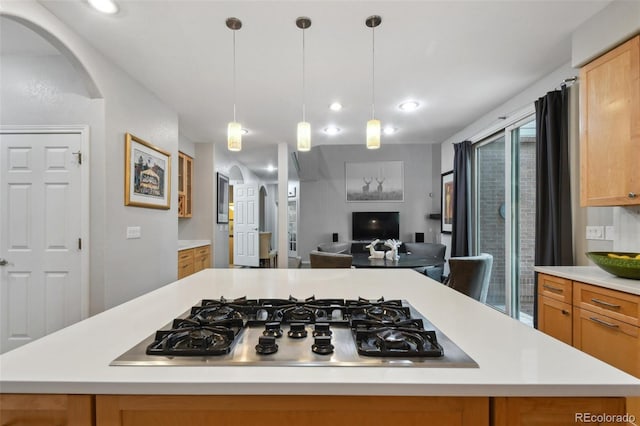 kitchen featuring arched walkways, light countertops, a center island, and stainless steel gas stovetop