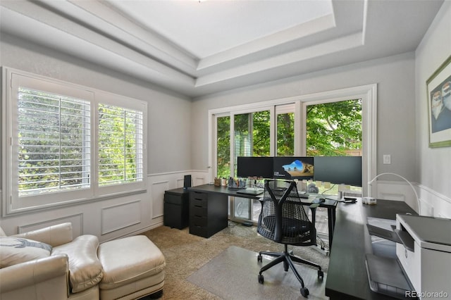 carpeted home office with wainscoting, a raised ceiling, and a decorative wall