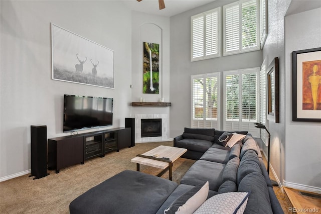 living room with a ceiling fan, baseboards, visible vents, and a high ceiling