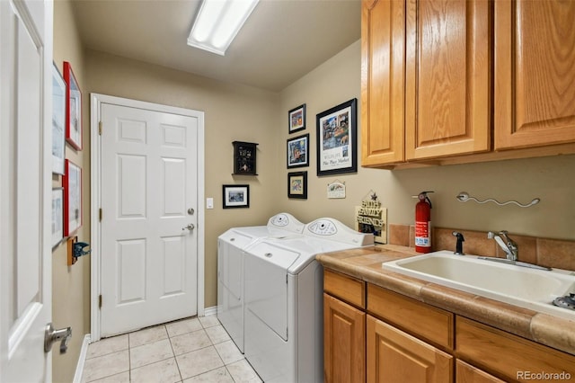 laundry area featuring cabinet space, light tile patterned floors, washer and dryer, and a sink