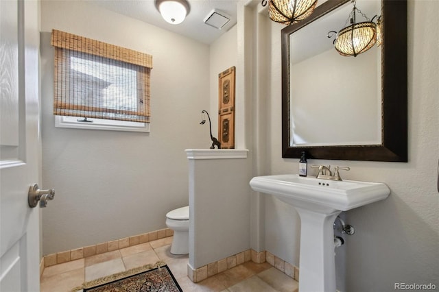 bathroom with toilet, tile patterned flooring, baseboards, and a sink