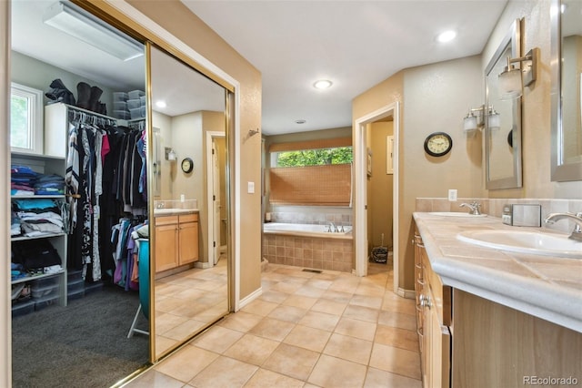 full bathroom with double vanity, a garden tub, a sink, and tile patterned floors