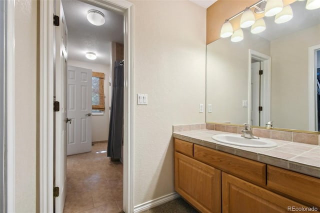 bathroom with vanity, baseboards, and tile patterned floors