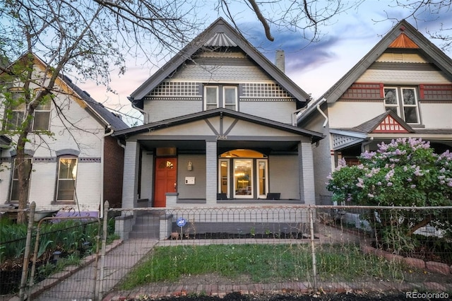 victorian house with brick siding, a fenced front yard, and covered porch