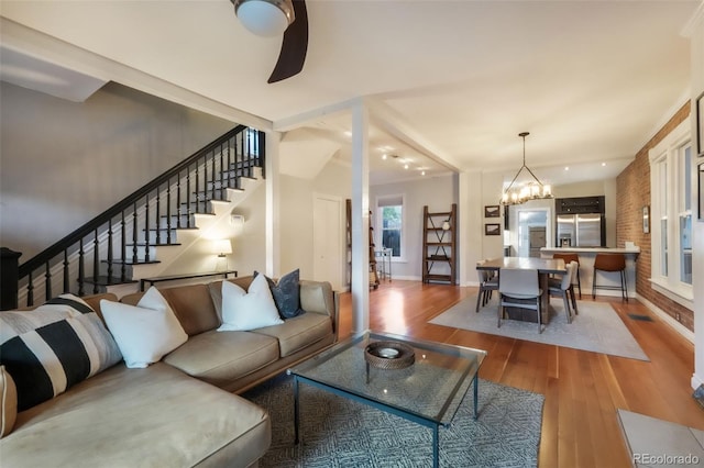 living room featuring stairs, baseboards, a notable chandelier, and hardwood / wood-style flooring