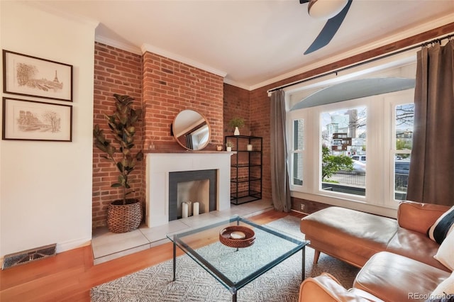 living room with visible vents, ornamental molding, wood finished floors, baseboards, and a ceiling fan