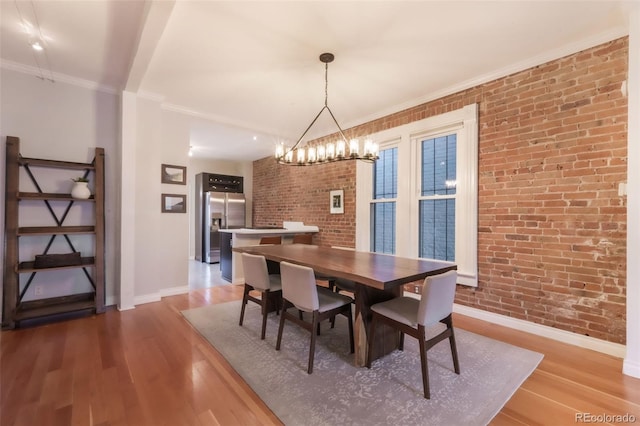 dining room featuring baseboards, wood finished floors, and brick wall