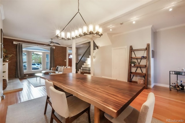 dining room with light wood-type flooring, baseboards, brick wall, and stairway