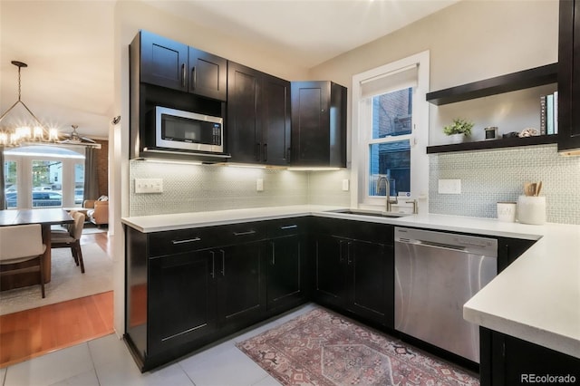 kitchen featuring a notable chandelier, a sink, light countertops, stainless steel appliances, and backsplash