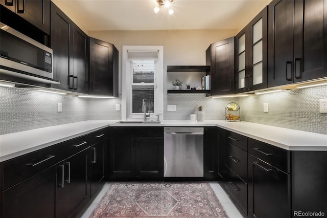 kitchen featuring decorative backsplash, appliances with stainless steel finishes, open shelves, a sink, and light countertops