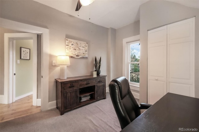 office space with baseboards, ceiling fan, and light carpet