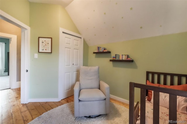 bedroom featuring wood-type flooring, baseboards, vaulted ceiling, and a closet