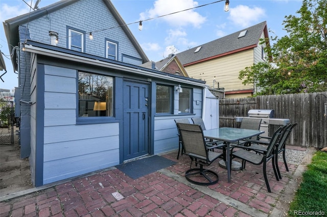 rear view of property featuring fence, outdoor dining space, and a patio area