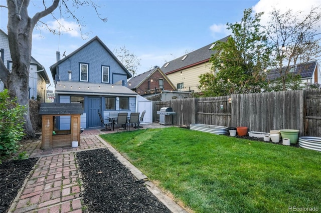rear view of house featuring a lawn, a fenced backyard, and a patio area
