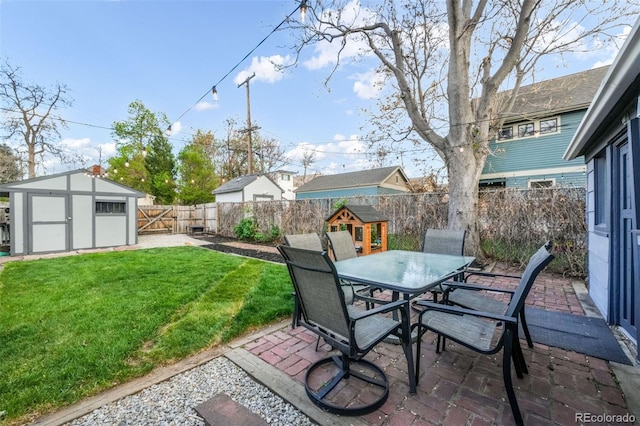 view of patio / terrace featuring an outdoor structure, a fenced backyard, a shed, and outdoor dining space