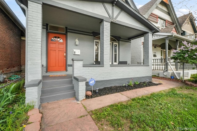 entrance to property with brick siding and a porch