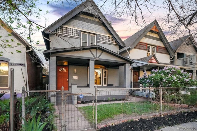 victorian house featuring a gate, a fenced front yard, a porch, and brick siding