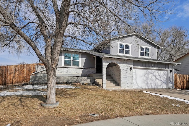 split level home with concrete driveway, brick siding, fence, and an attached garage