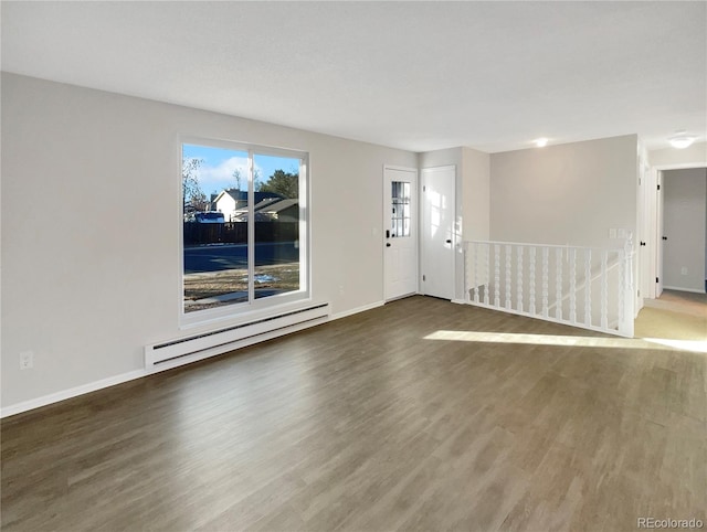 empty room with hardwood / wood-style flooring and a baseboard heating unit