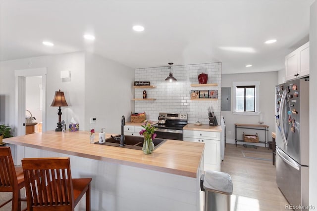 kitchen featuring white cabinetry, stainless steel appliances, and butcher block countertops