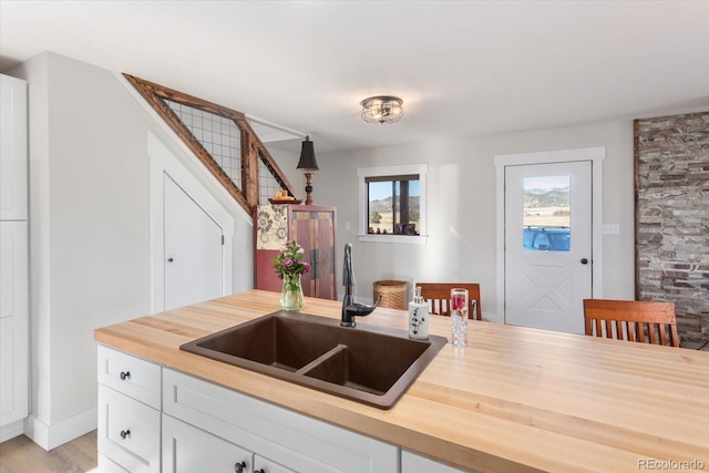 kitchen with wood counters, sink, white cabinets, and light wood-type flooring