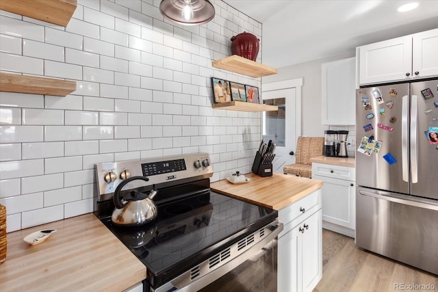 kitchen featuring wood counters, tasteful backsplash, light hardwood / wood-style flooring, appliances with stainless steel finishes, and white cabinets