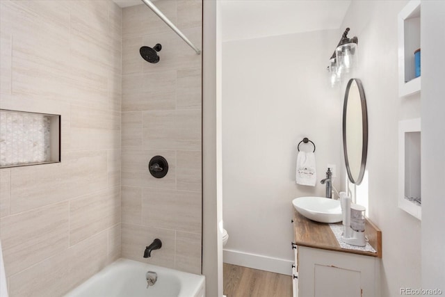 full bathroom featuring vanity, tiled shower / bath, hardwood / wood-style flooring, and toilet