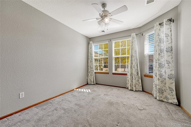 spare room with ceiling fan, a textured ceiling, and light colored carpet