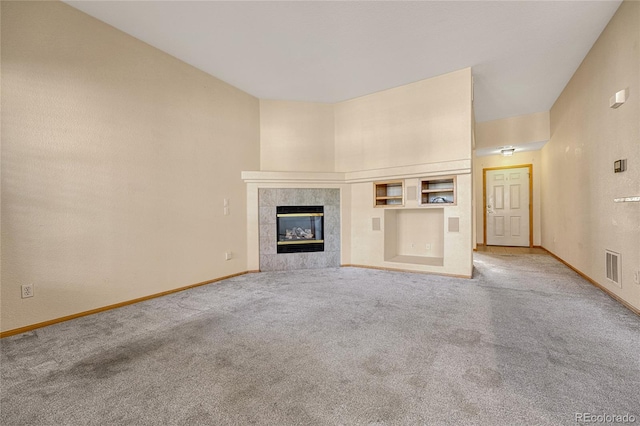 unfurnished living room with carpet floors and a tile fireplace