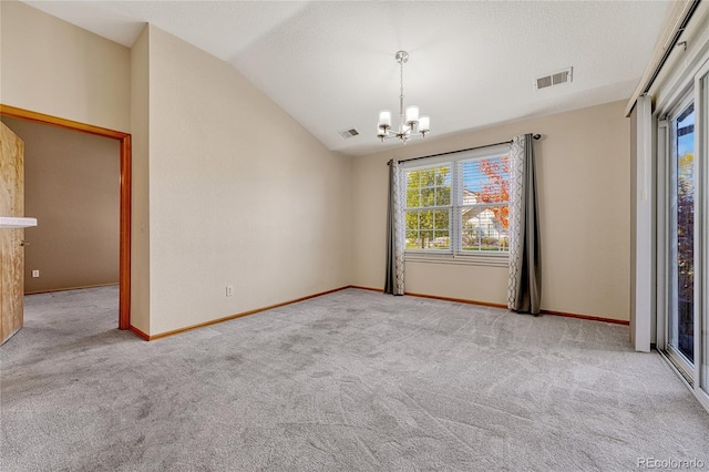 carpeted empty room with an inviting chandelier, a textured ceiling, and vaulted ceiling