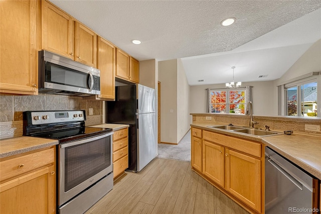 kitchen with light hardwood / wood-style flooring, vaulted ceiling, appliances with stainless steel finishes, and sink