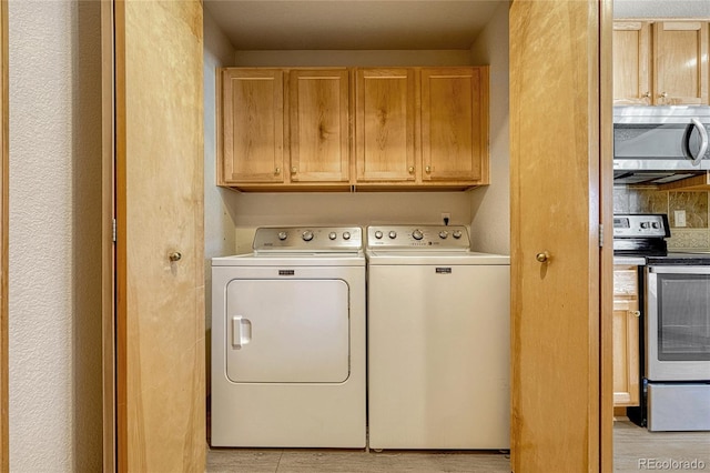 clothes washing area featuring washer and dryer, light hardwood / wood-style floors, and cabinets