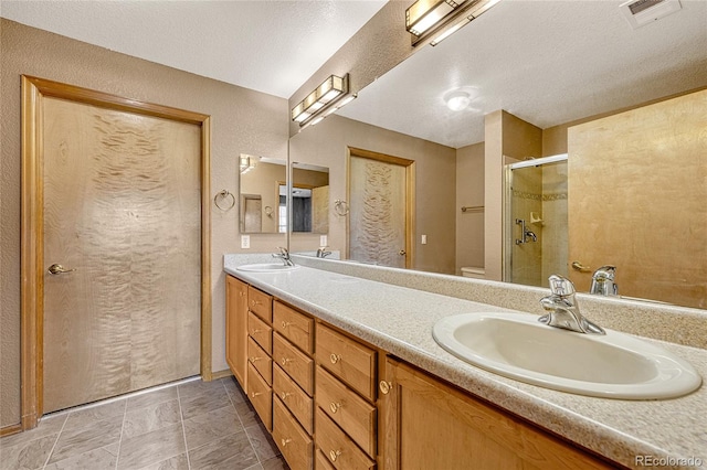 bathroom featuring vanity, toilet, a textured ceiling, and a shower with door