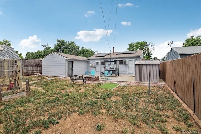 rear view of property with a patio, a shed, and solar panels