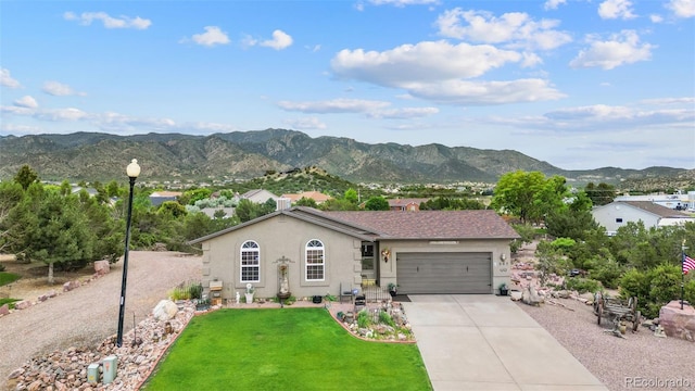 ranch-style home with a garage, a mountain view, and a front lawn