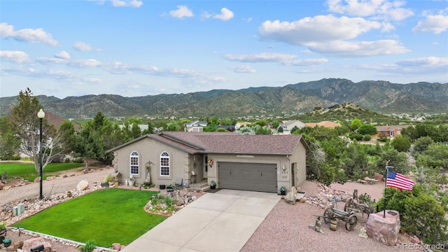 view of front of house with a garage, a mountain view, and a front lawn