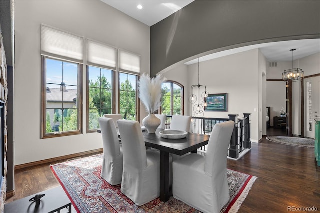 8000 Raphael Ln, Littleton, CO 80125 - dining room featuring a chandelier, dark wood-style floors, arched walkways, a towering ceiling, and recessed lighting