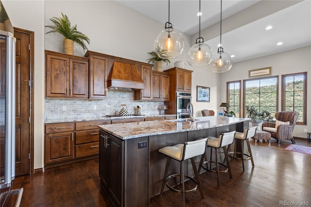 8000 Raphael Ln, Littleton, CO 80125 - kitchen with custom exhaust hood, dark wood-type flooring, a kitchen breakfast bar, backsplash, and light stone countertops