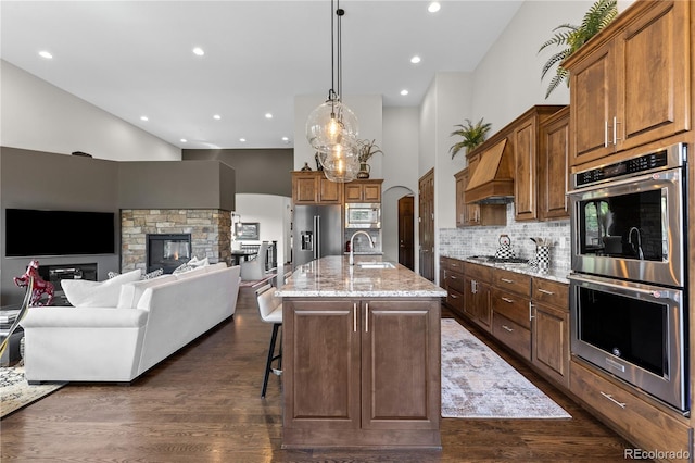 8000 Raphael Ln, Littleton, CO 80125 - kitchen with appliances with stainless steel finishes, premium range hood, high vaulted ceiling, light stone countertops, and dark wood-type flooring