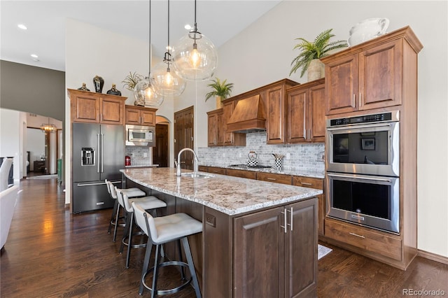 8000 Raphael Ln, Littleton, CO 80125 - kitchen with appliances with stainless steel finishes, premium range hood, dark wood finished floors, a high ceiling, and backsplash