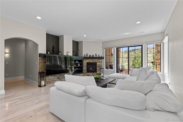 8000 Raphael Ln, Littleton, CO 80125 - living area featuring a stone fireplace, light wood-style floors, arched walkways, and recessed lighting