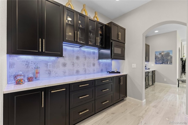 8000 Raphael Ln, Littleton, CO 80125 - kitchen with arched walkways, dark cabinetry, black microwave, and glass insert cabinets