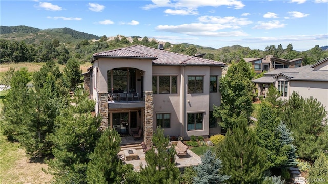 8000 Raphael Ln, Littleton, CO 80125 - view of front of property with stucco siding, a balcony, a mountain view, a tiled roof, and stone siding