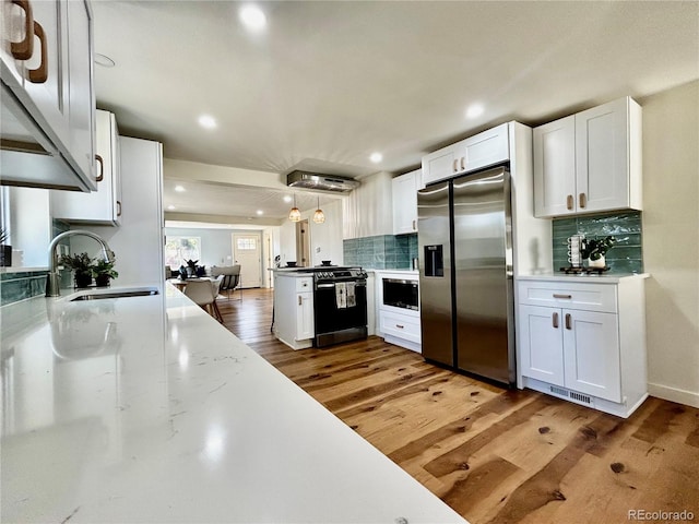 kitchen featuring hardwood / wood-style floors, sink, stainless steel appliances, hanging light fixtures, and white cabinetry