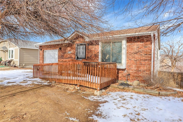 view of front of property with a garage, brick siding, and a wooden deck