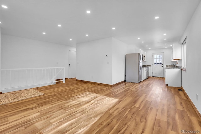 unfurnished living room featuring light wood-style flooring, baseboards, and recessed lighting